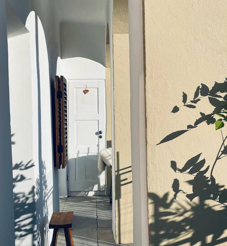 Heller Außenbereich mit Bögen und einer weißen Tür, beleuchtet von der Morgensonne.