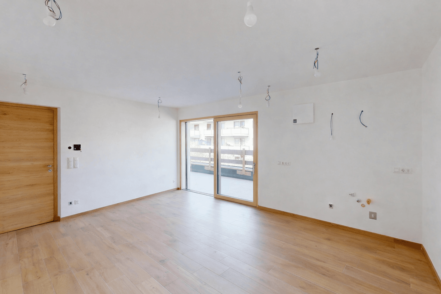 Moderner Wohnbereich mit hellem Holzboden und breiter Glasfront zum Außenbereich.