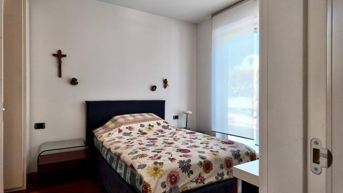 Helles Schlafzimmer mit Holzboden, floraler Bettwäsche und Fenster.