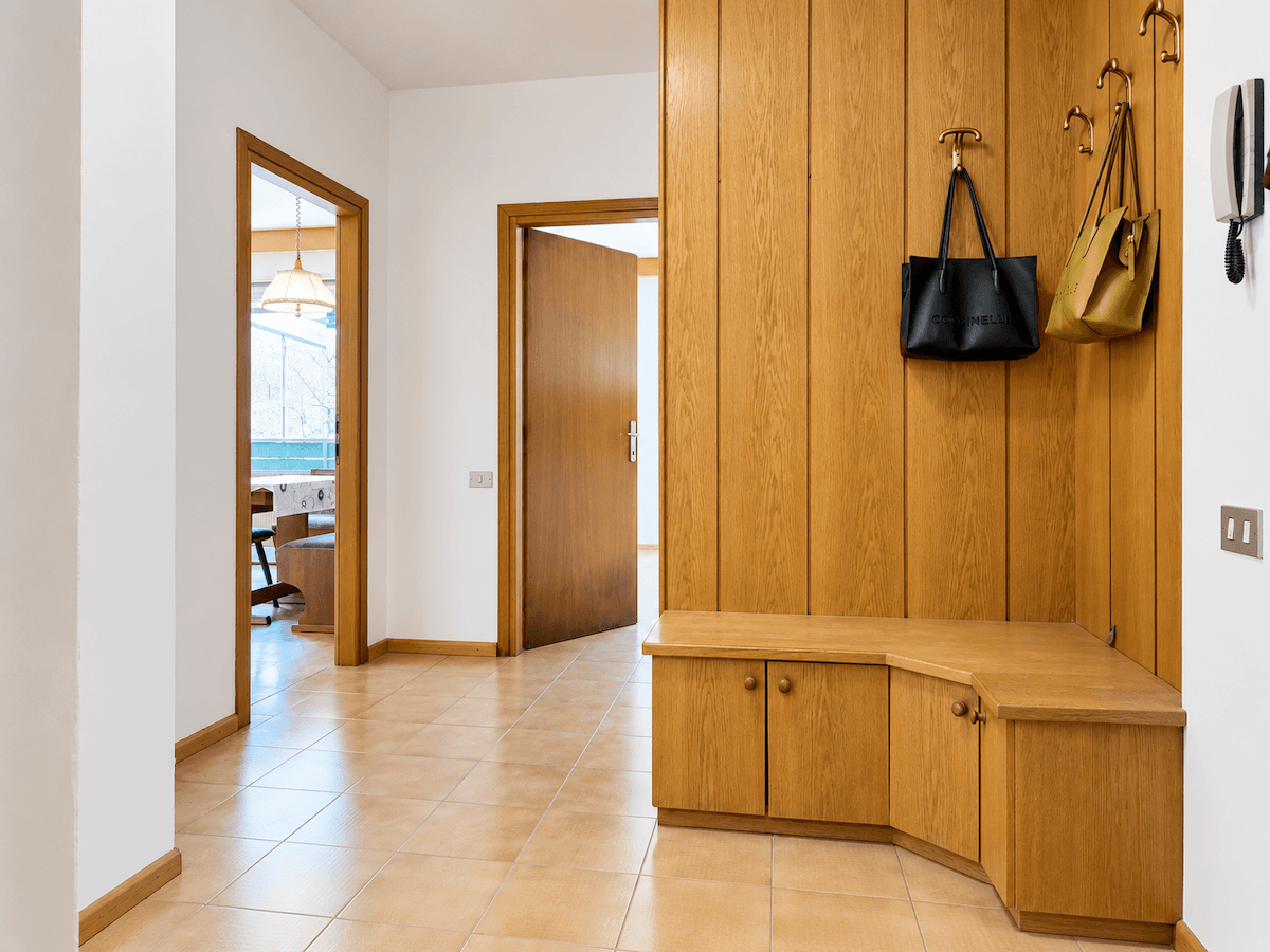 Eingangsbereich mit Fliesenboden, Holzvertäfelung und praktischer Garderobenbank.