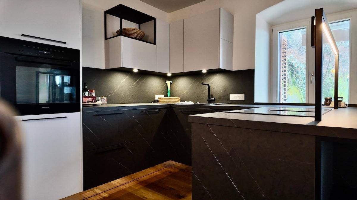 Detailansicht der modernen Küche mit Induktionskochfeld, integriertem Backofen und hochwertigen Geräten.