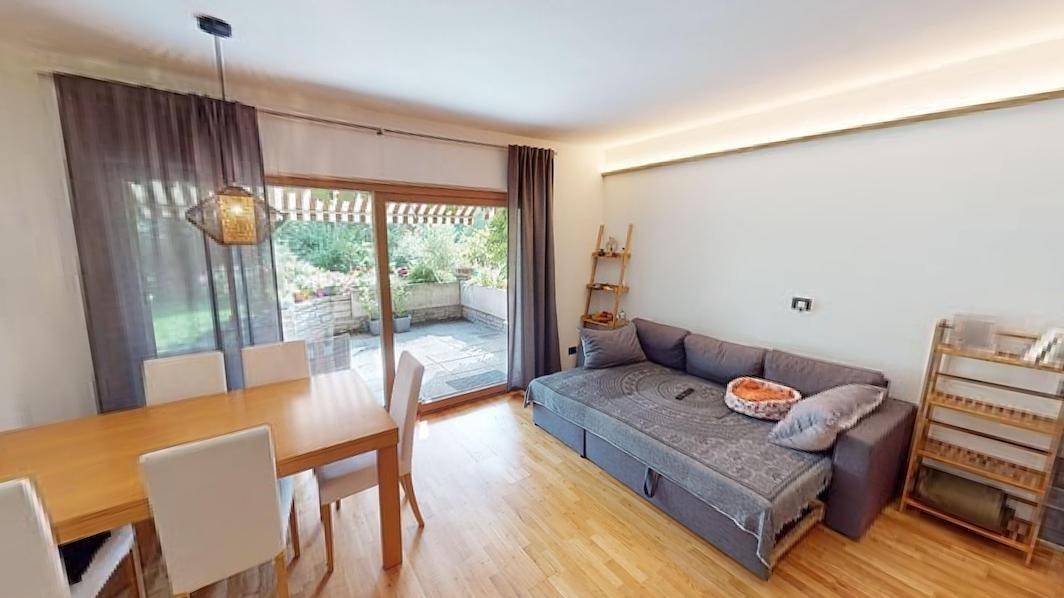 Gemütlicher Wohn-Essbereich mit Holzboden, Sofa und direktem Zugang zur Außenterrasse.