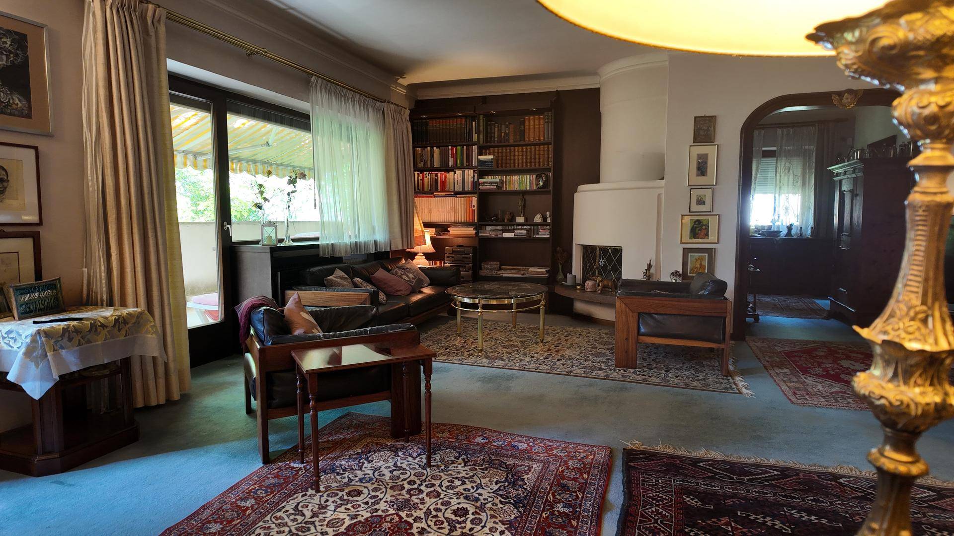 Wohnzimmer mit Kamin, Bücherregalen, Teppichboden und Zugang zu einem Außenbereich.