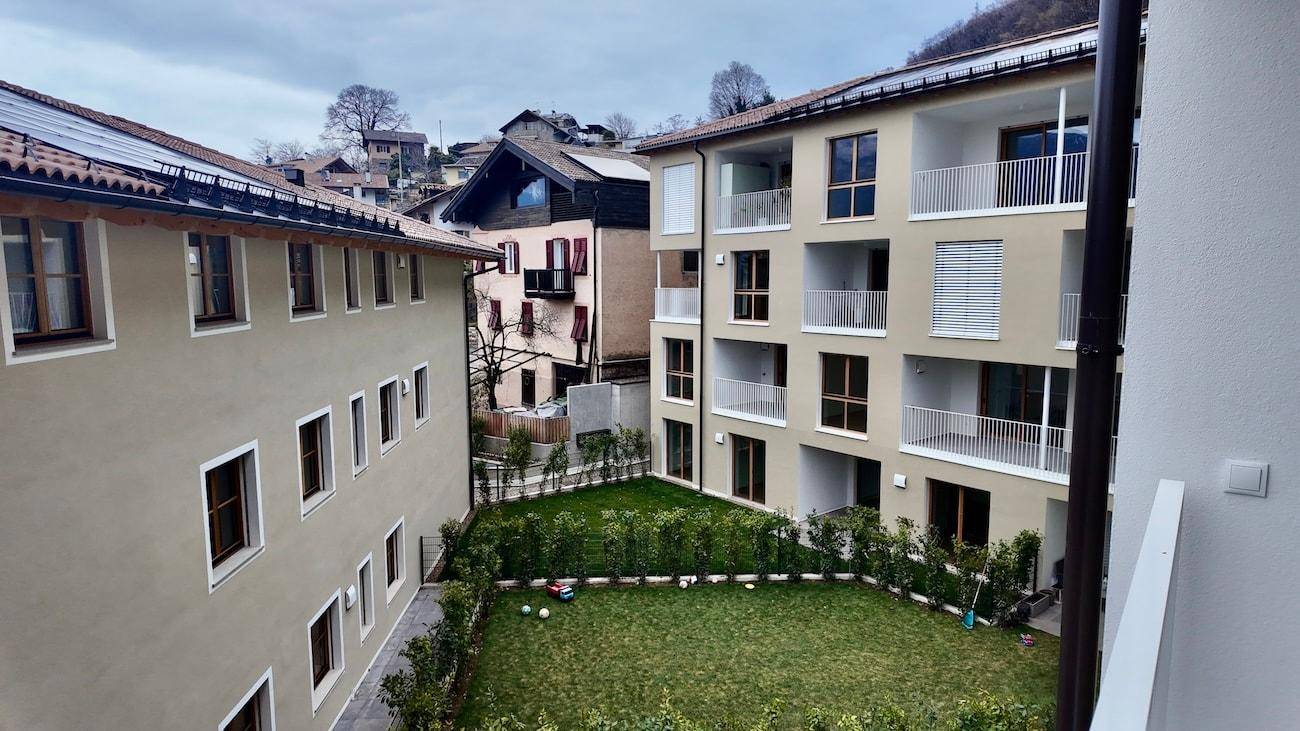 Moderne Wohngebäude mit Balkonen und einem gemeinsamen Gartenbereich in einer ländlichen Umgebung.
