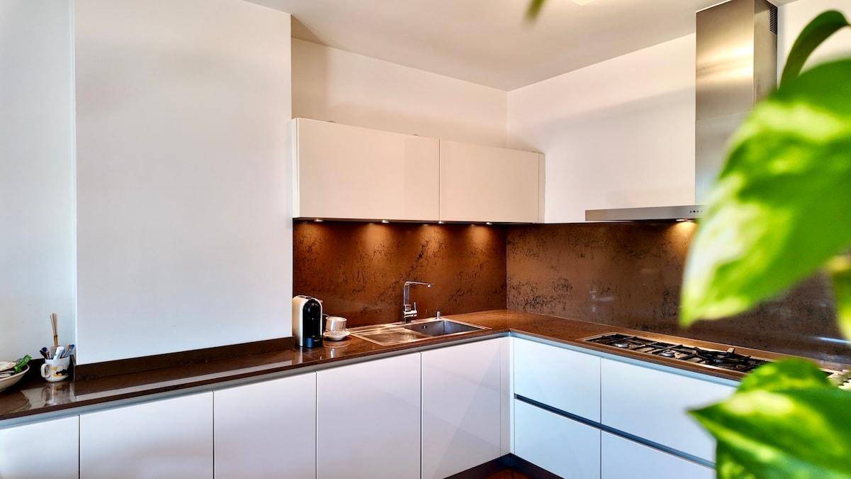 Moderne Küche mit weißen Schränken, dunkler Arbeitsplatte und integrierten Geräten.