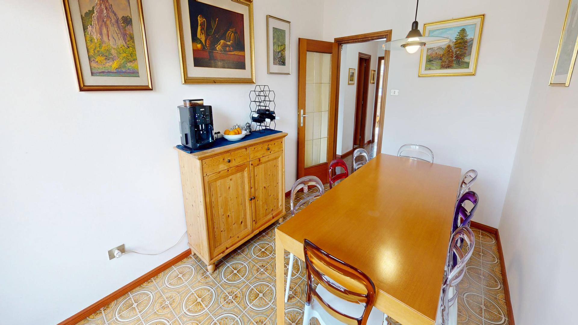 Essbereich mit Holztisch, Sideboard und gemustertem Fliesenboden.