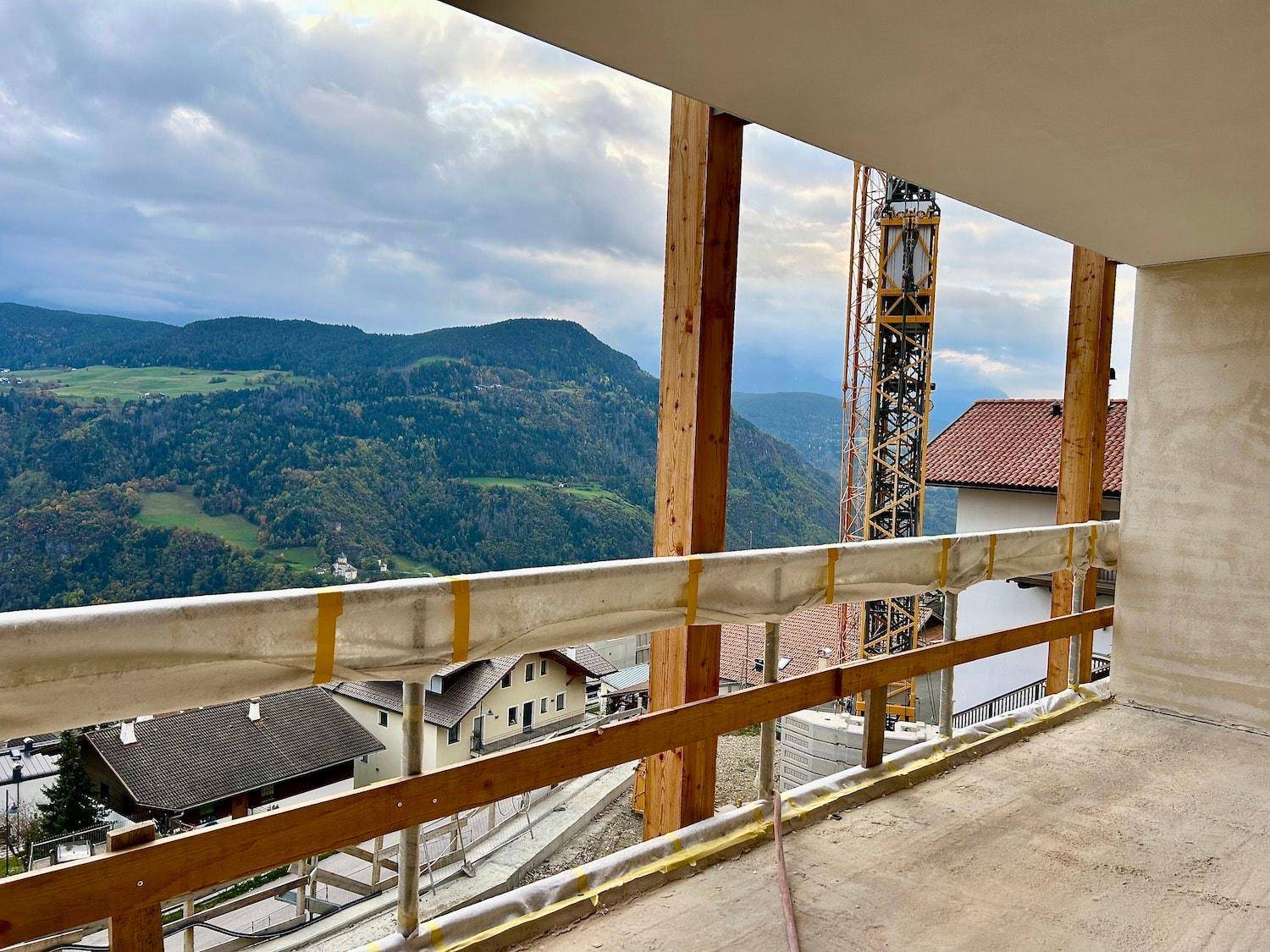 Unfertiger Balkon mit Holzbalken und weitem Blick auf die umliegende Berglandschaft.