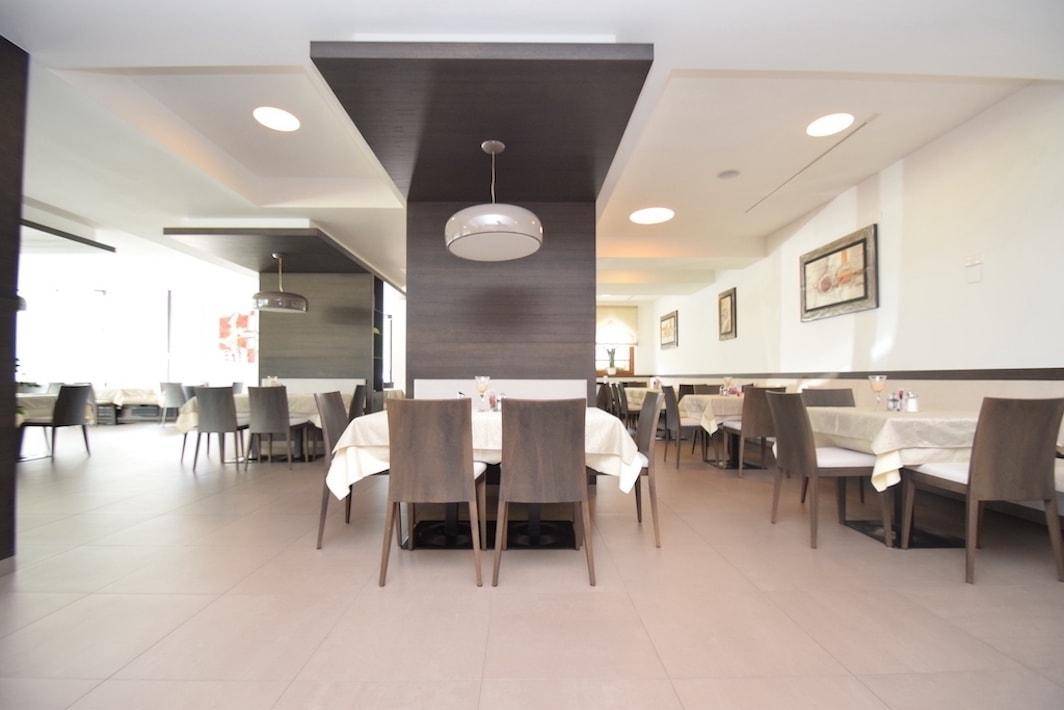 Geräumiger Speisesaal mit vielen Tischen, bequemen Stühlen und moderner Beleuchtung.