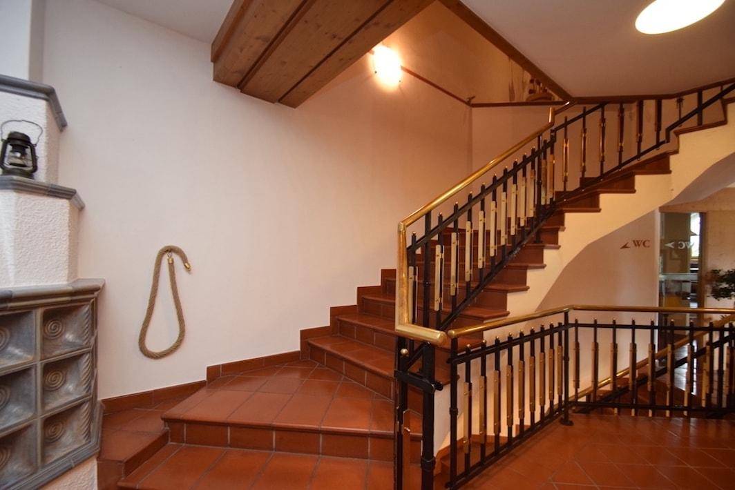 Rustikales Treppenhaus mit Terrakottafliesen, schmiedeeisernem Geländer und dekorativem Seil an der Wand.