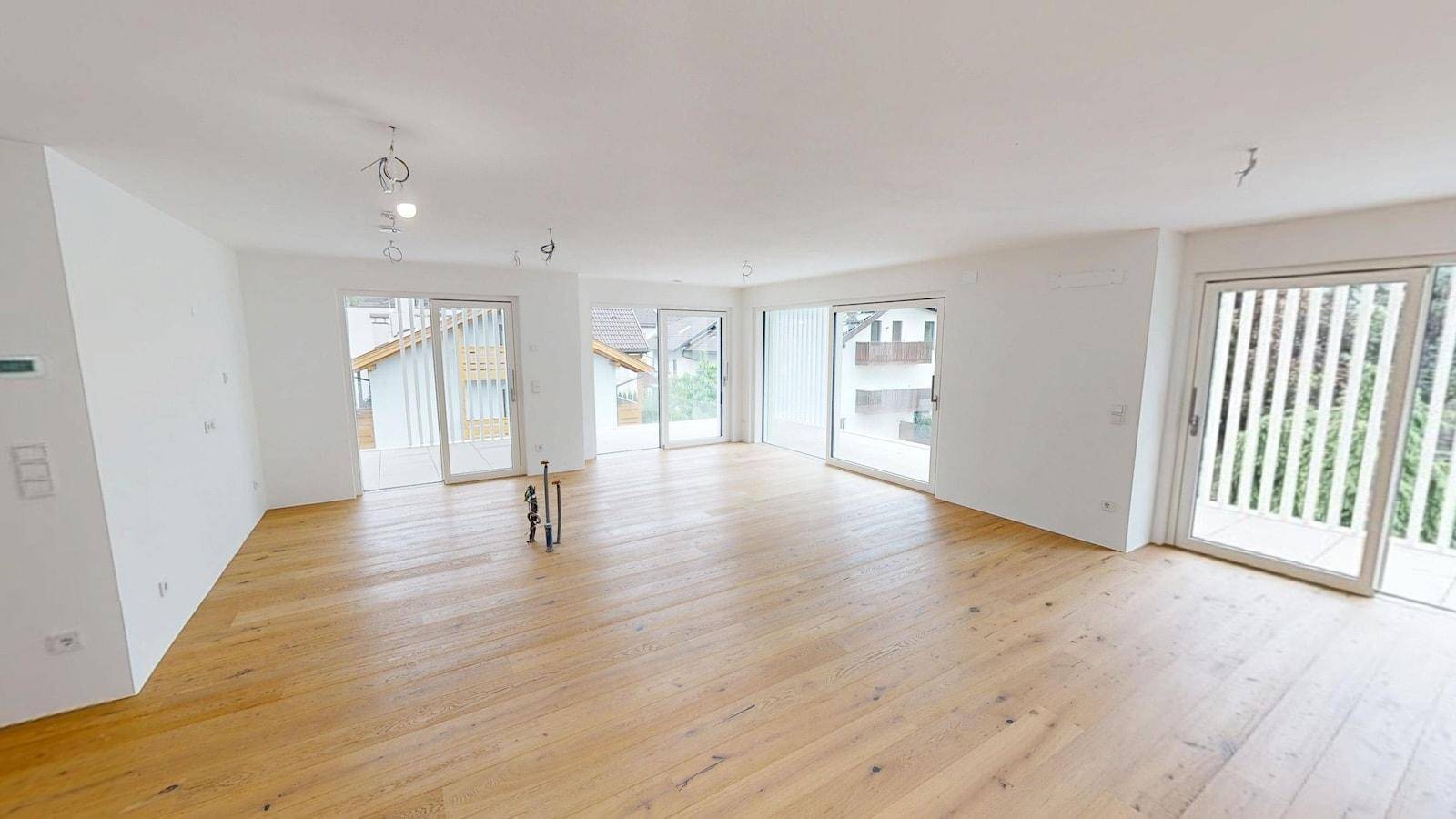 Geräumiger, heller Wohnbereich mit neuem Parkettboden und mehreren Zugängen zu Balkonen oder Terrassen.