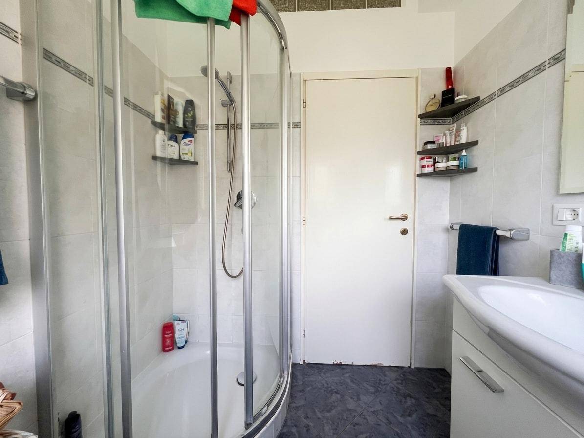 Modernes Badezimmer mit Duschkabine, Waschbecken und hellen Fliesen.