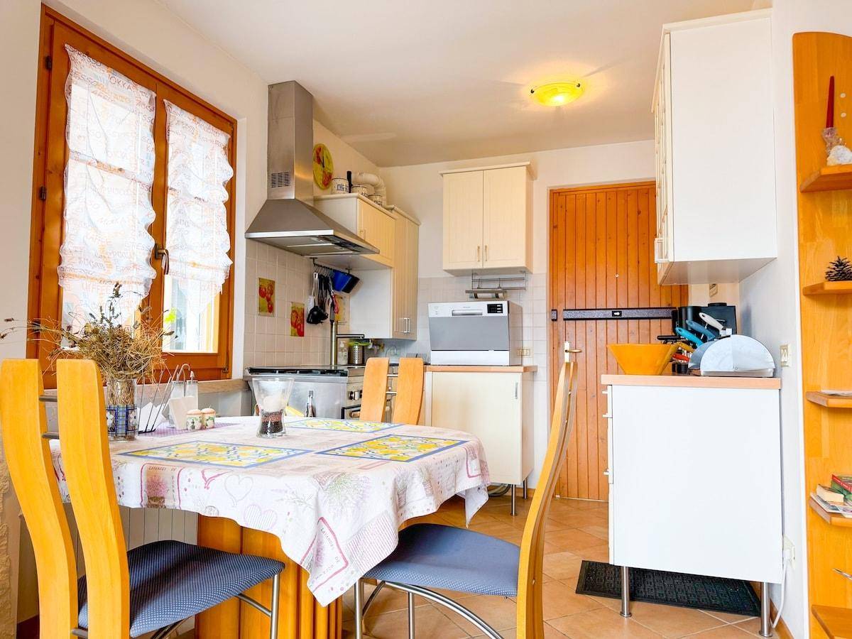 Funktionale Küche mit Esstisch, weißen Schränken und einem Fenster für natürliches Licht.