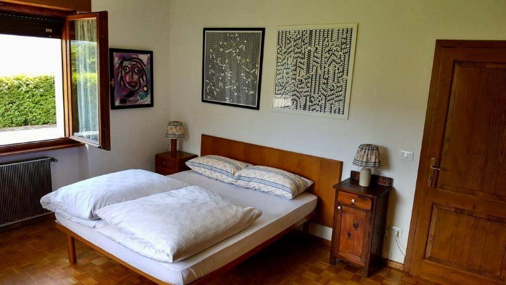 Schlafzimmer mit Doppelbett, Nachttischen und Kunstwerken an den Wänden.
