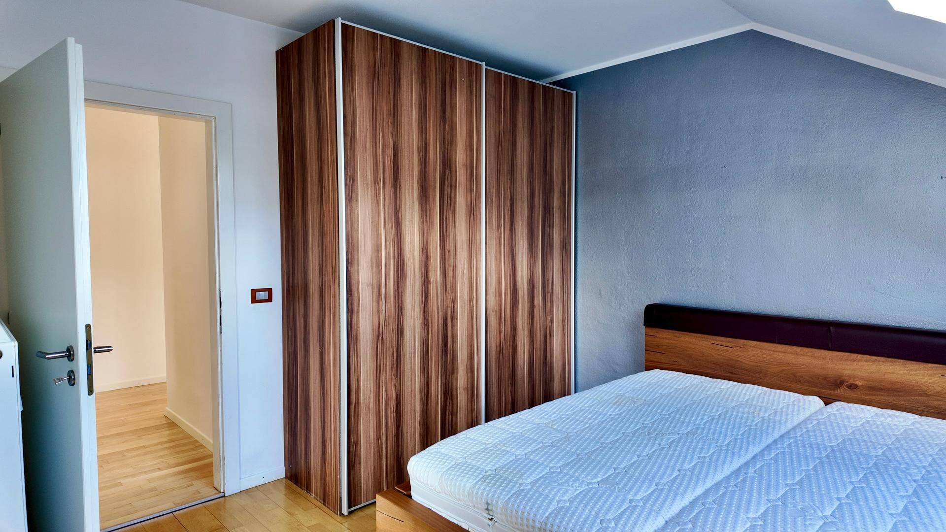Schlafzimmer mit Holzbett und großem Kleiderschrank, der viel Stauraum bietet.