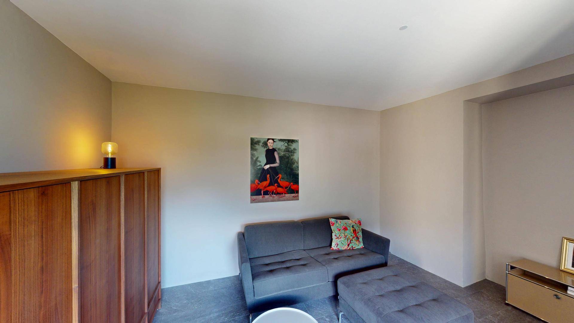 Helles Wohnzimmer mit beigem Sofa, Kunst an der Wand und schlichter Einrichtung.