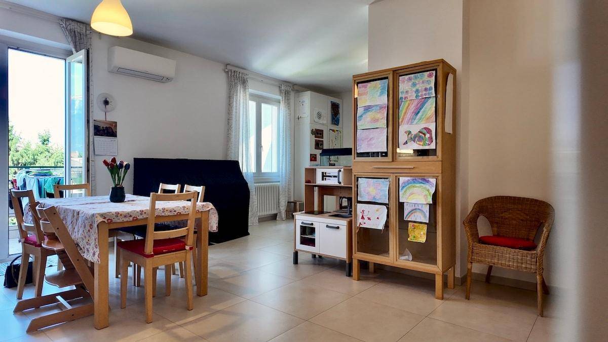 Heller Wohn- und Essbereich mit Zugang zum Balkon, Kindermöbeln und Klimaanlage.