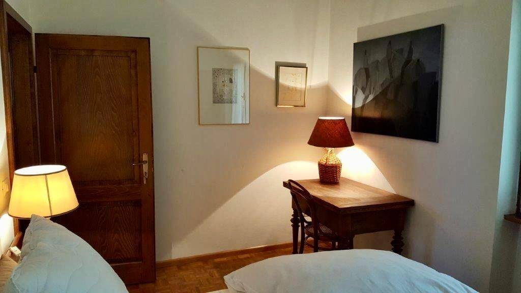 Gemütliches Schlafzimmer mit Holzboden, Schreibtisch und indirekter Beleuchtung.