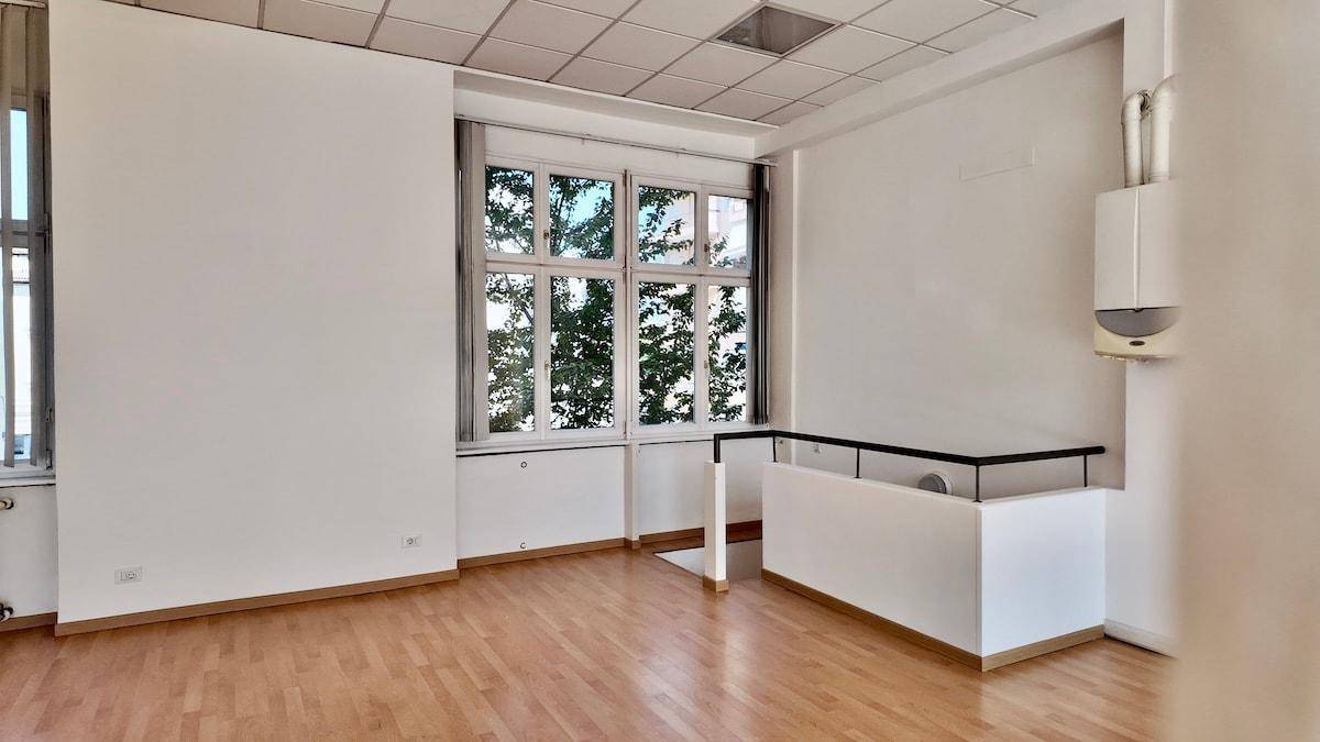 Detailansicht eines Bürobereichs mit Holzboden, Fenster und einer kleinen Theke.