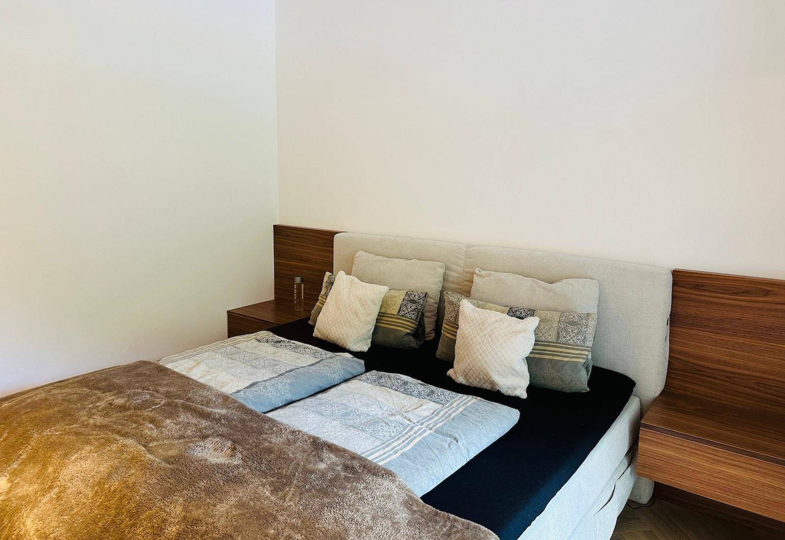 Schlafzimmer mit Doppelbett, Holzkopfteil und Nachttischen.