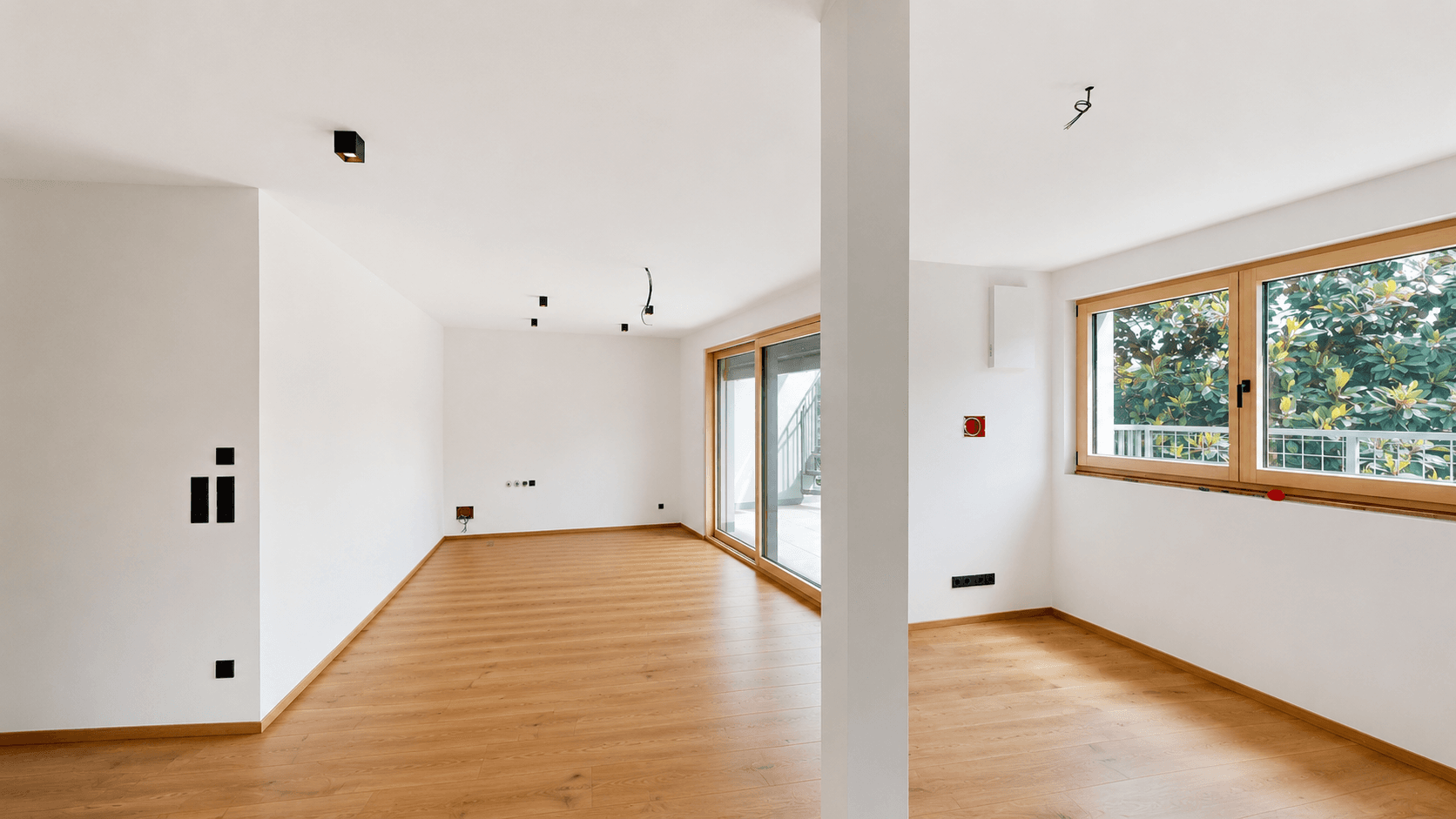 Geräumiger, heller Raum mit Holzboden und Balkonzugang, bereit für die individuelle Gestaltung.