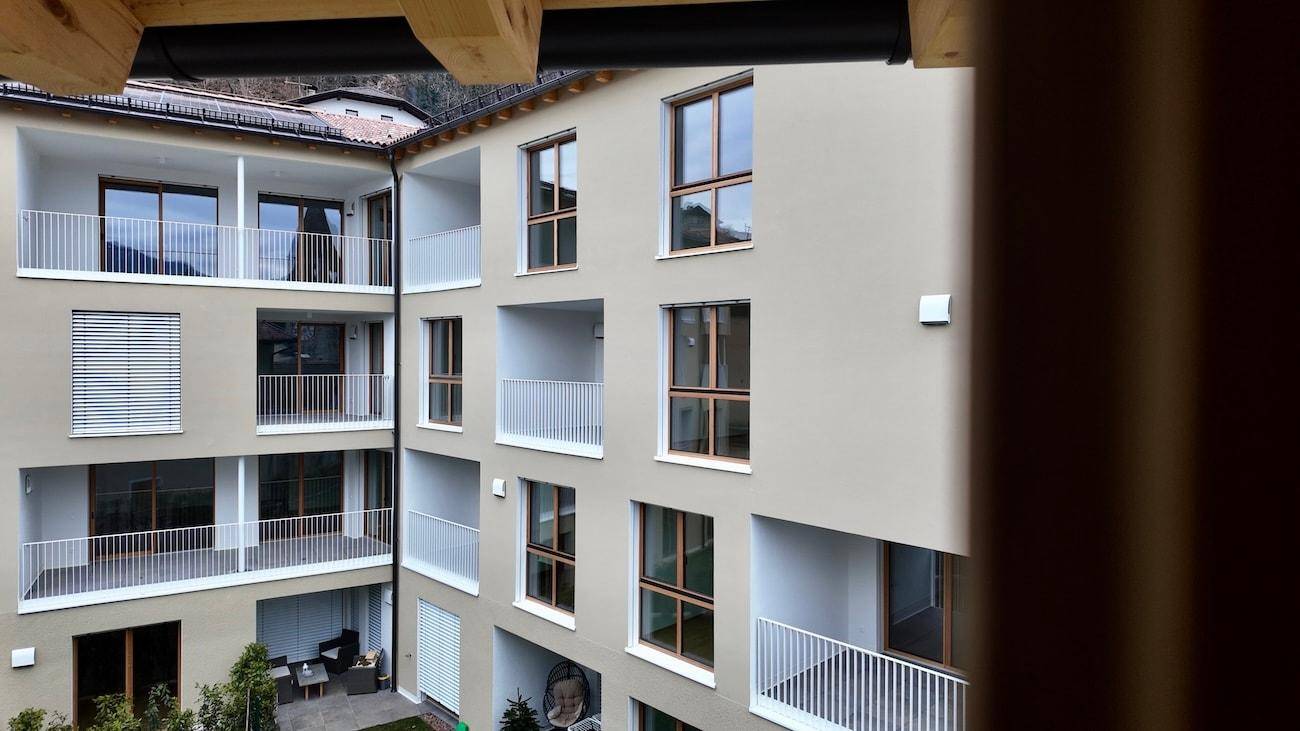 Blick auf einen Innenhof eines modernen Wohnkomplexes mit mehreren Balkonen und Fenstern.
