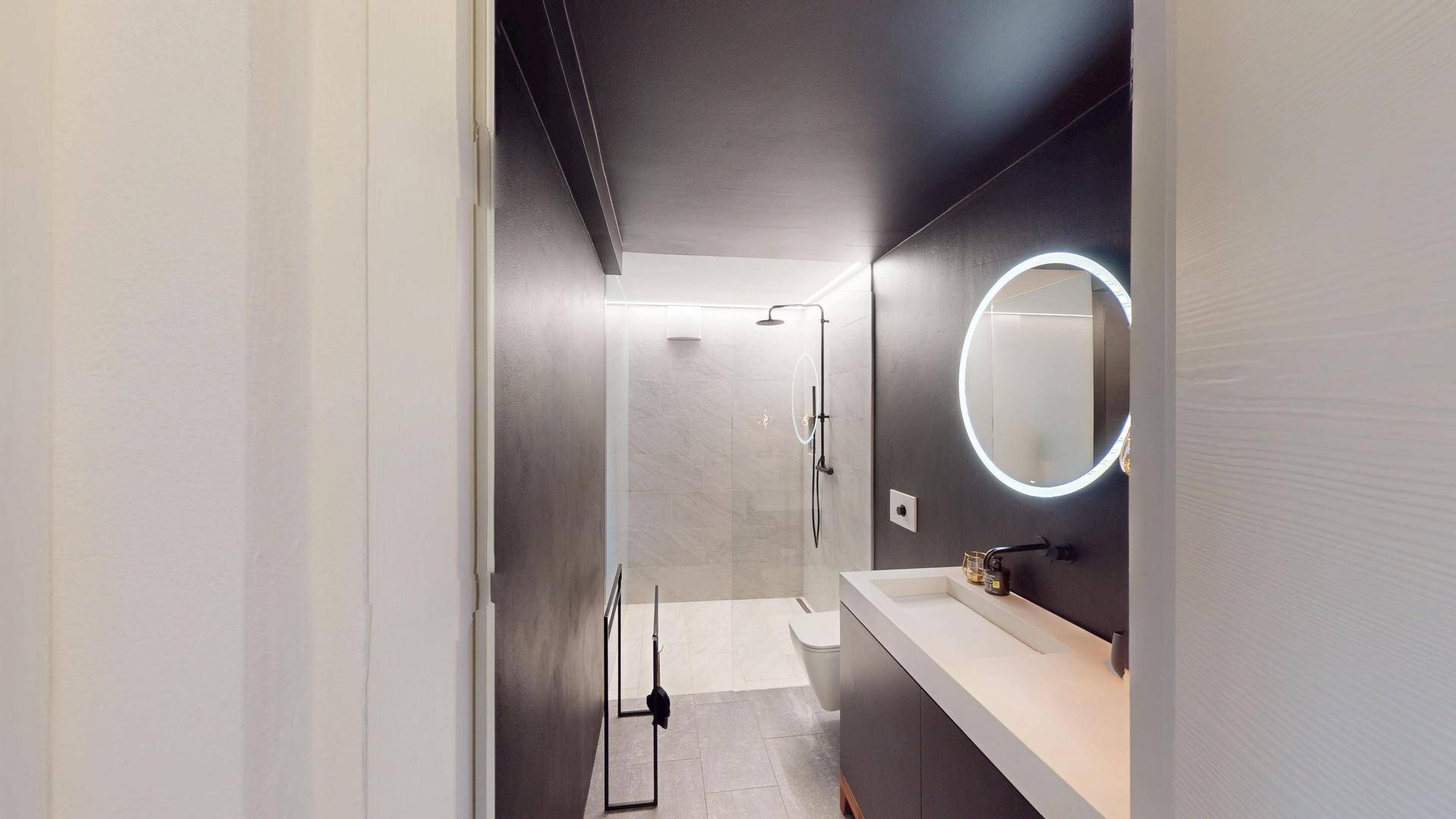 Modernes Badezimmer mit minimalistischem Design, beleuchtetem Spiegel und begehbarer Dusche.