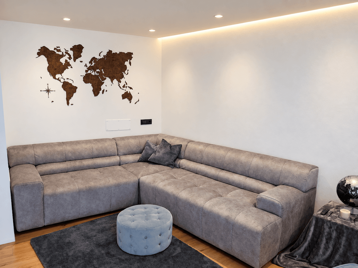 Gemütliches Wohnzimmer mit großem Ecksofa, Holzboden und dekorativer Weltkarte an der Wand.