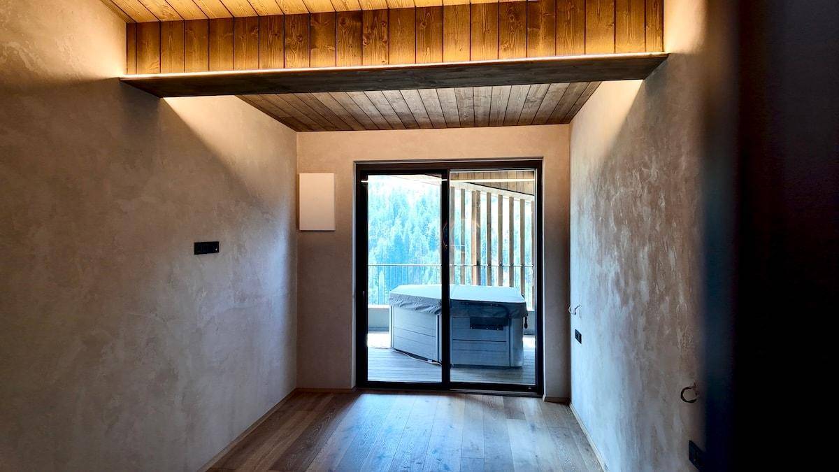 Schlafzimmer mit Holzboden, Holzdecke und direktem Zugang zum Balkon mit Whirlpool.
