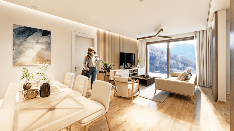 Offener Wohn-Essbereich mit Holzboden, moderner Einrichtung und Bergblick durch große Fenster.