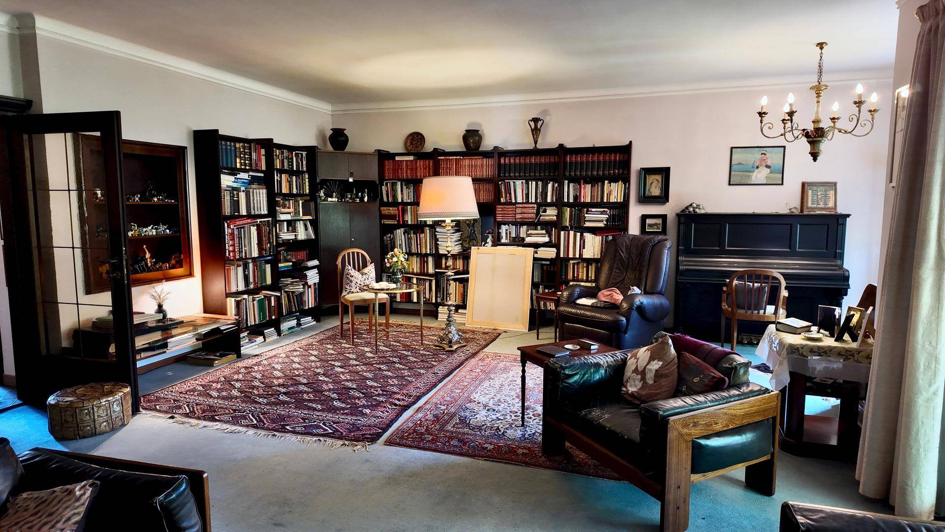 Großes Wohnzimmer mit umfangreicher Bibliothek, Klavier und gemütlichen Sitzgelegenheiten.