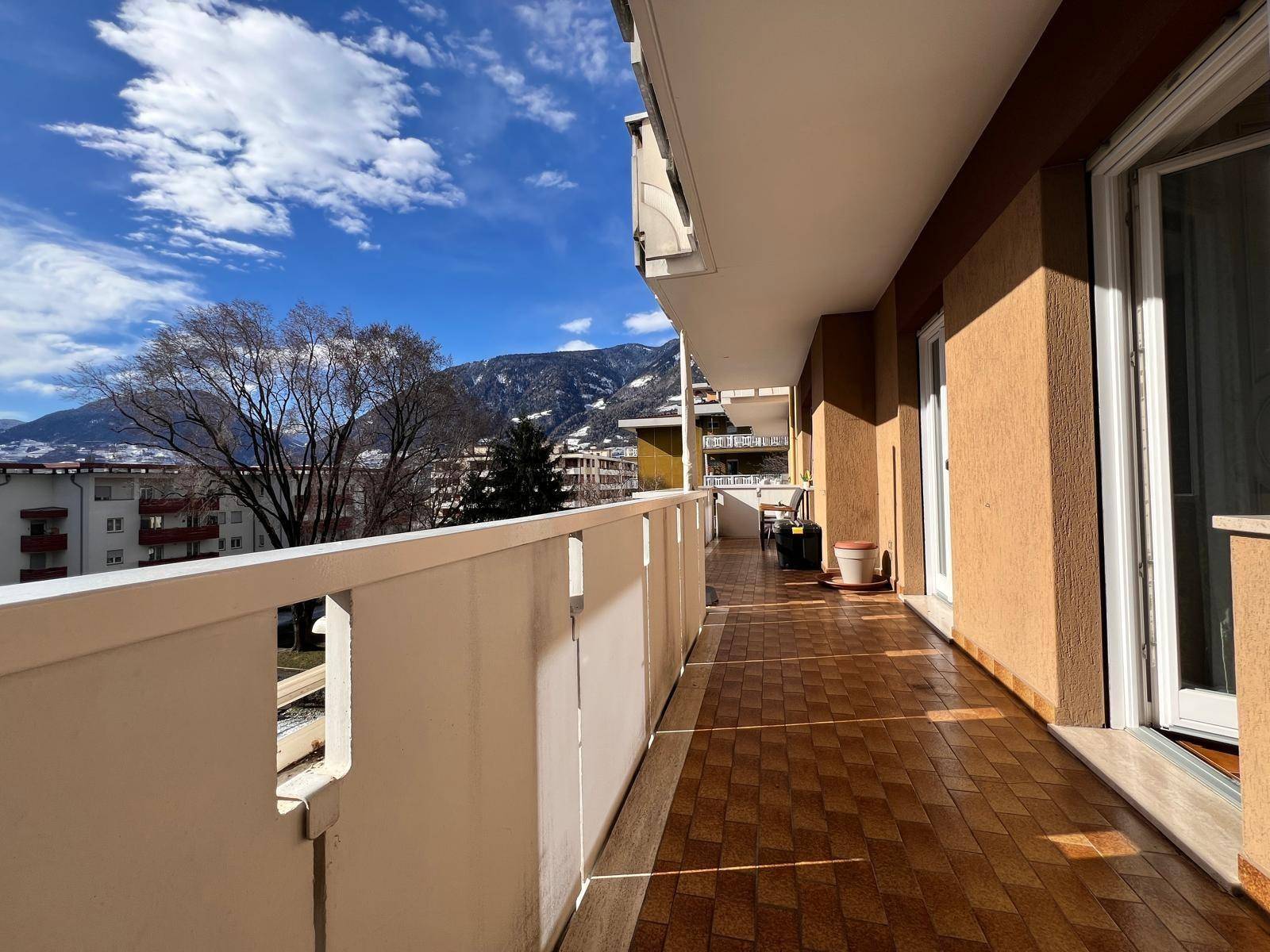 Langer Balkon mit Fliesenboden und weitem Blick auf die umliegende Berglandschaft.