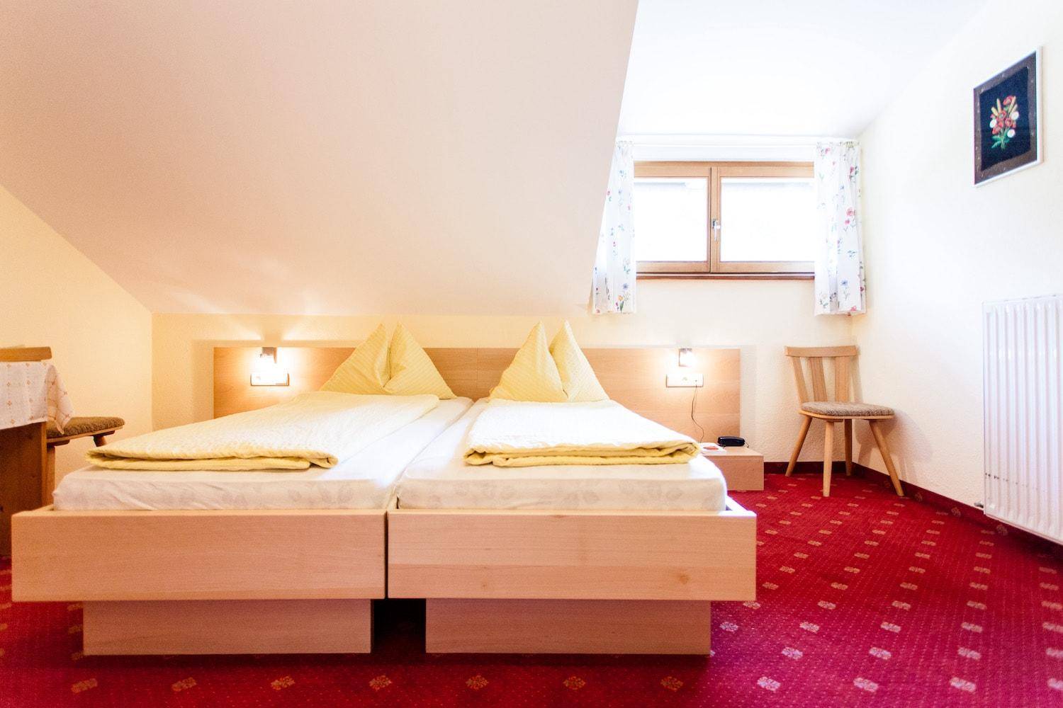 Schlafzimmer mit zwei Einzelbetten, rotem Teppichboden und Dachschräge.