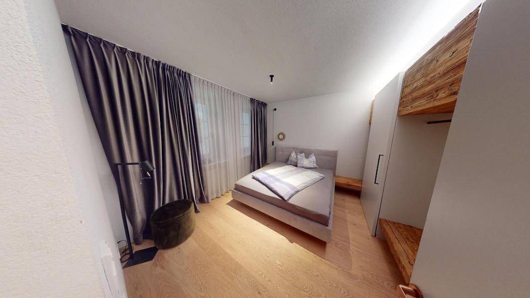 Helles Schlafzimmer mit Holzboden, großem Bett und integrierten Holzschränken.