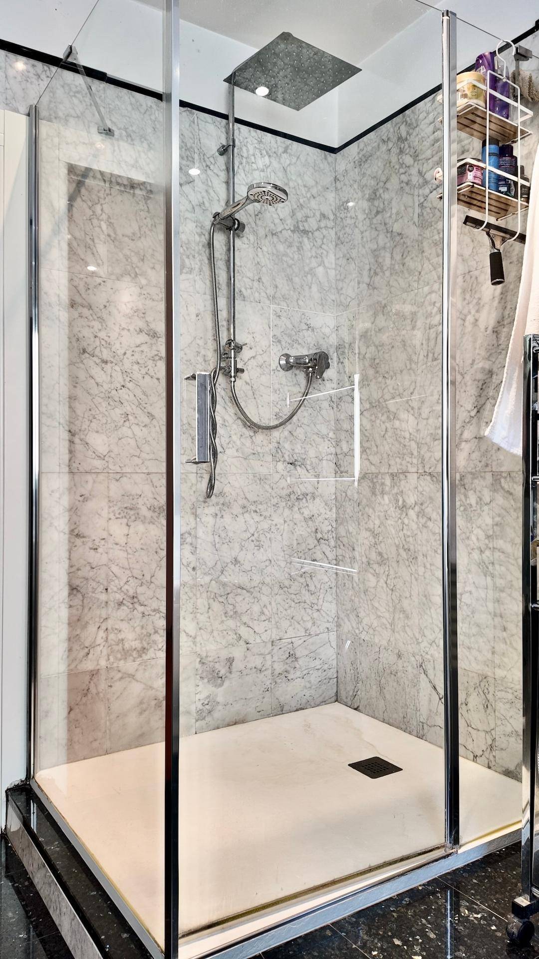Geräumige Duschkabine mit Regendusche und Marmorverkleidung.