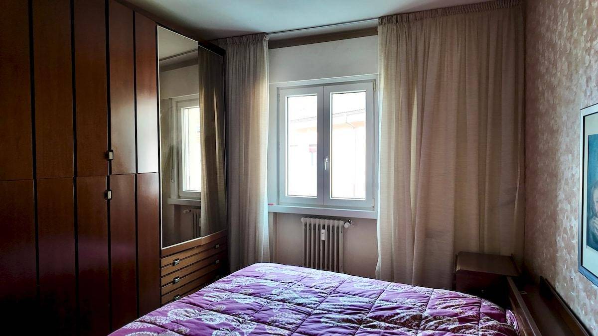 Schlafzimmer mit Doppelbett, großem Kleiderschrank und Fenster mit viel Tageslicht.
