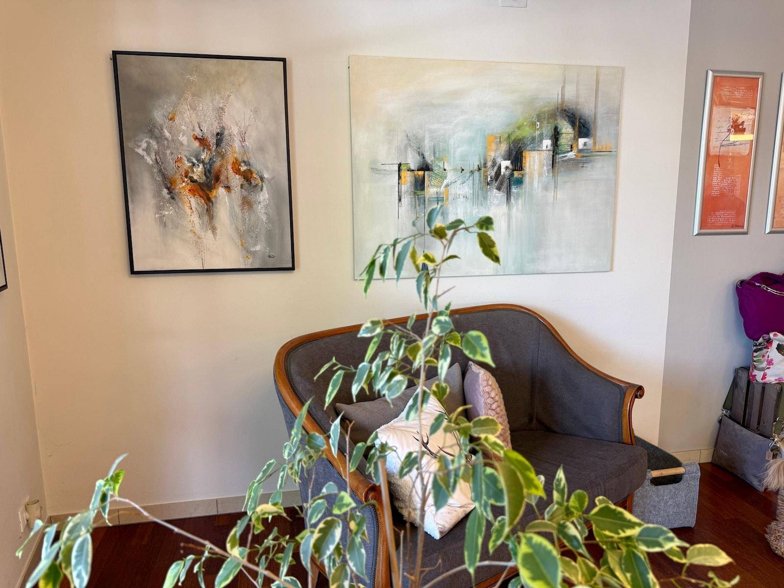 Detailansicht des Wartebereichs mit Kunstwerken und einem dekorativen Sofa.