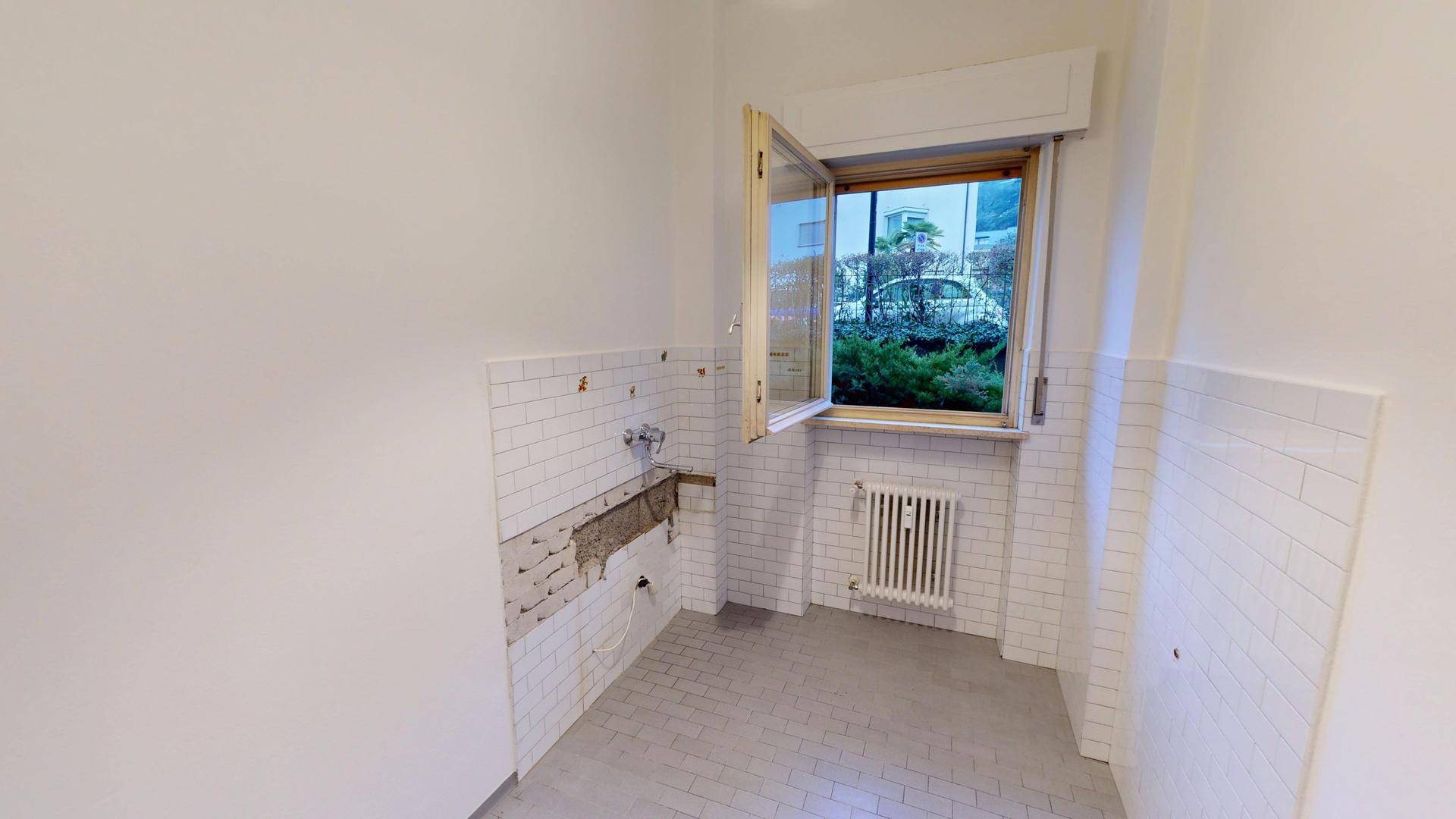 Unfertige Küche mit weißen Fliesen und einem Fenster, bereit für die Installation der Küchenzeile.