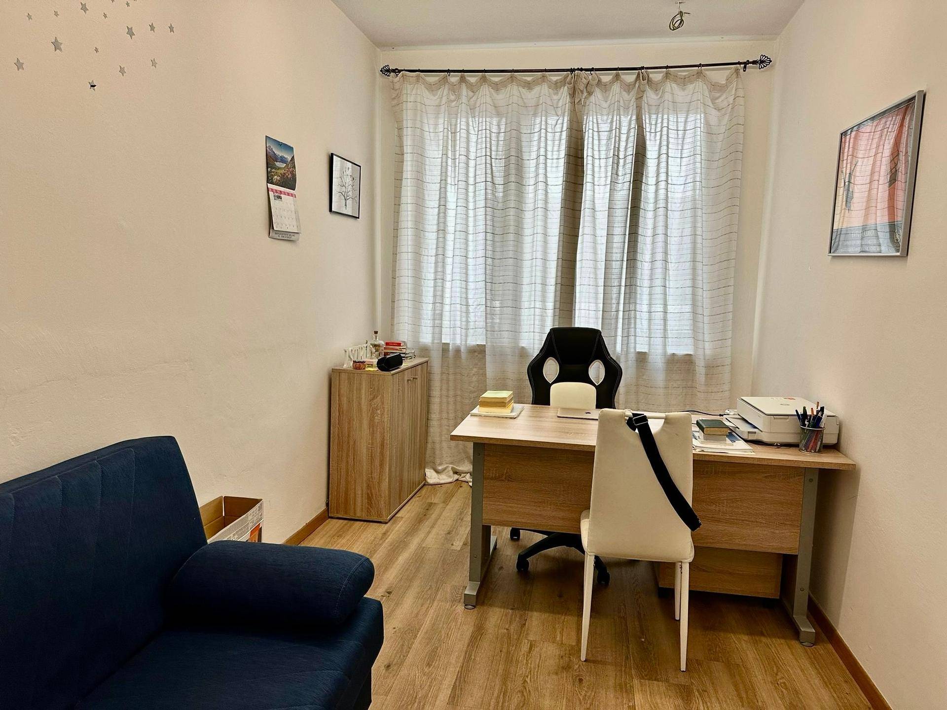 Gemütliches Einzelbüro mit Schreibtisch, Sofa und Vorhängen für Privatsphäre.
