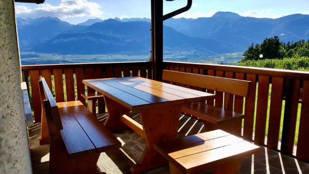 Überdachter Balkon mit rustikalem Holztisch und Bänken, bietet einen weiten Bergblick.