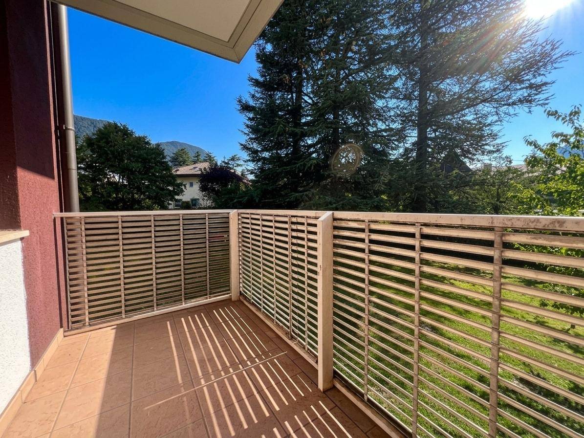Sonniger Balkon mit Fliesenboden und weitem Blick ins Grüne.