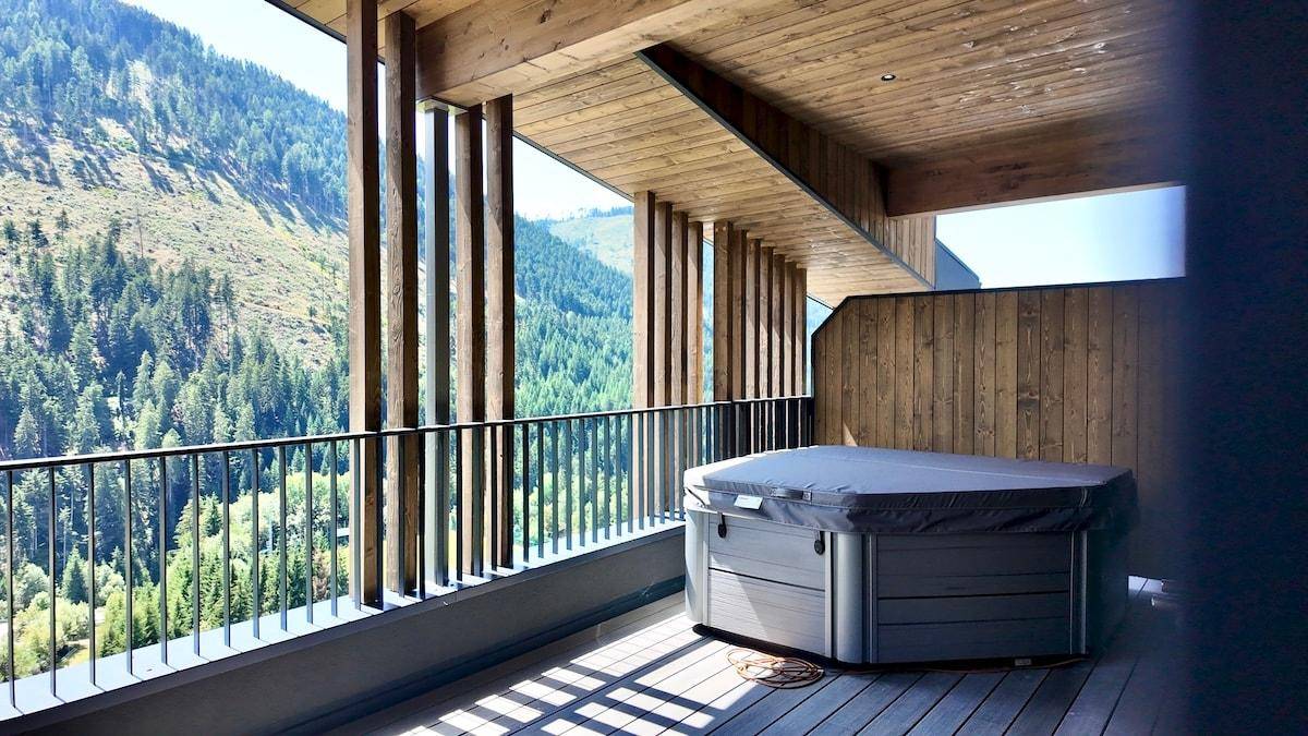 Großer Balkon mit Whirlpool und herrlichem Blick auf die bewaldeten Berghänge.
