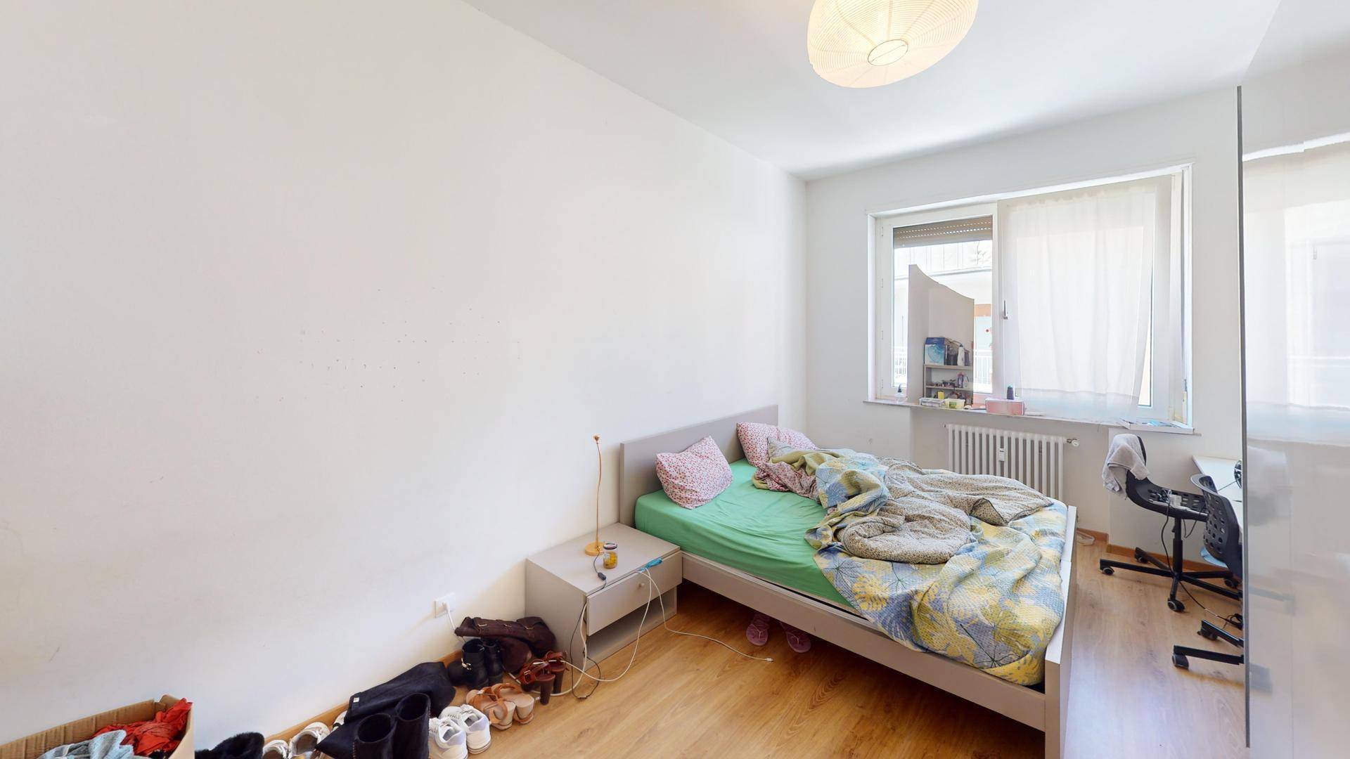 Schlafzimmer mit Holzboden, Bett und Fenster mit Blick nach draußen.