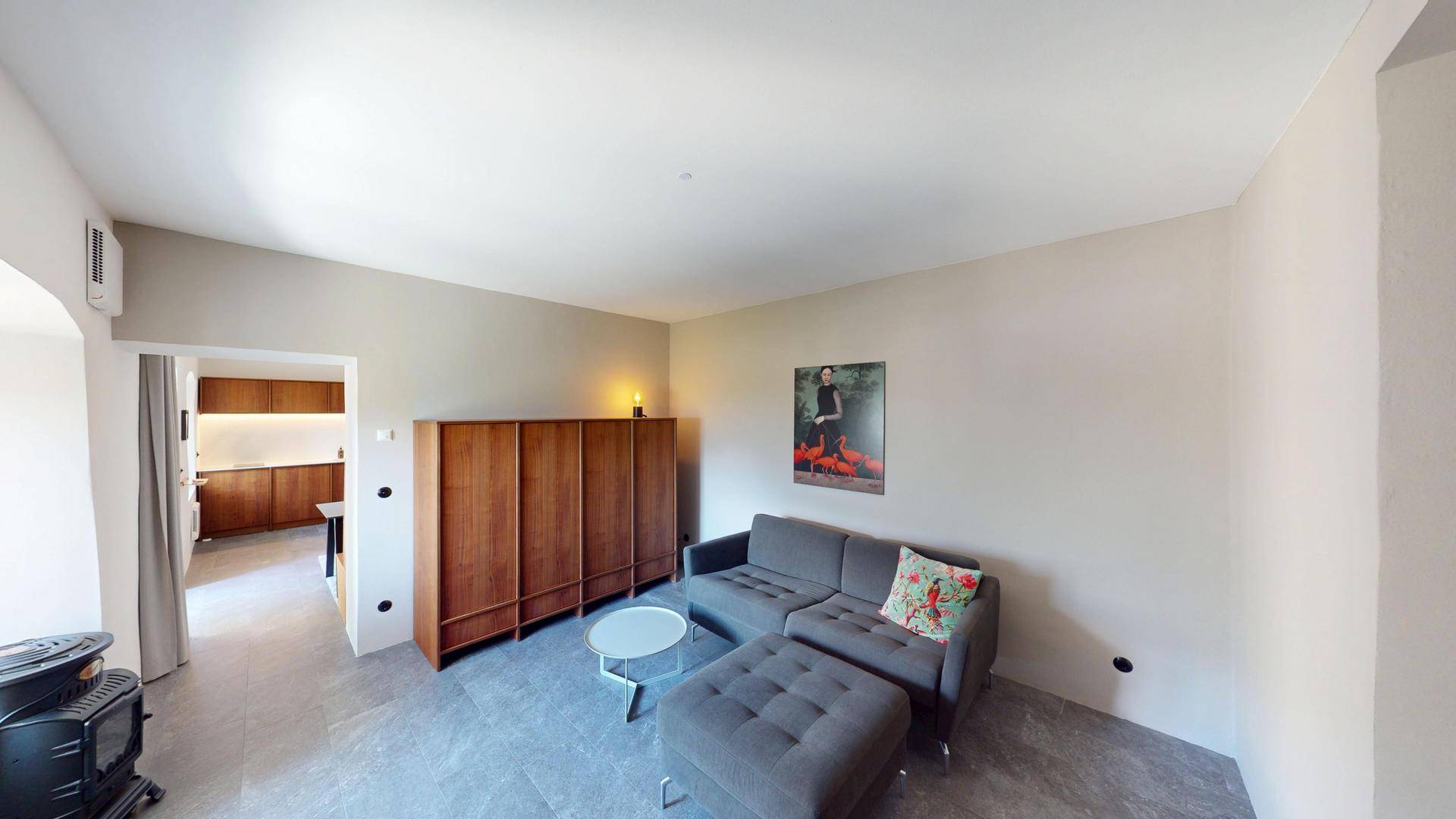 Gemütliches Wohnzimmer mit Sofa, Holzelementen und Blick auf den Küchenbereich.