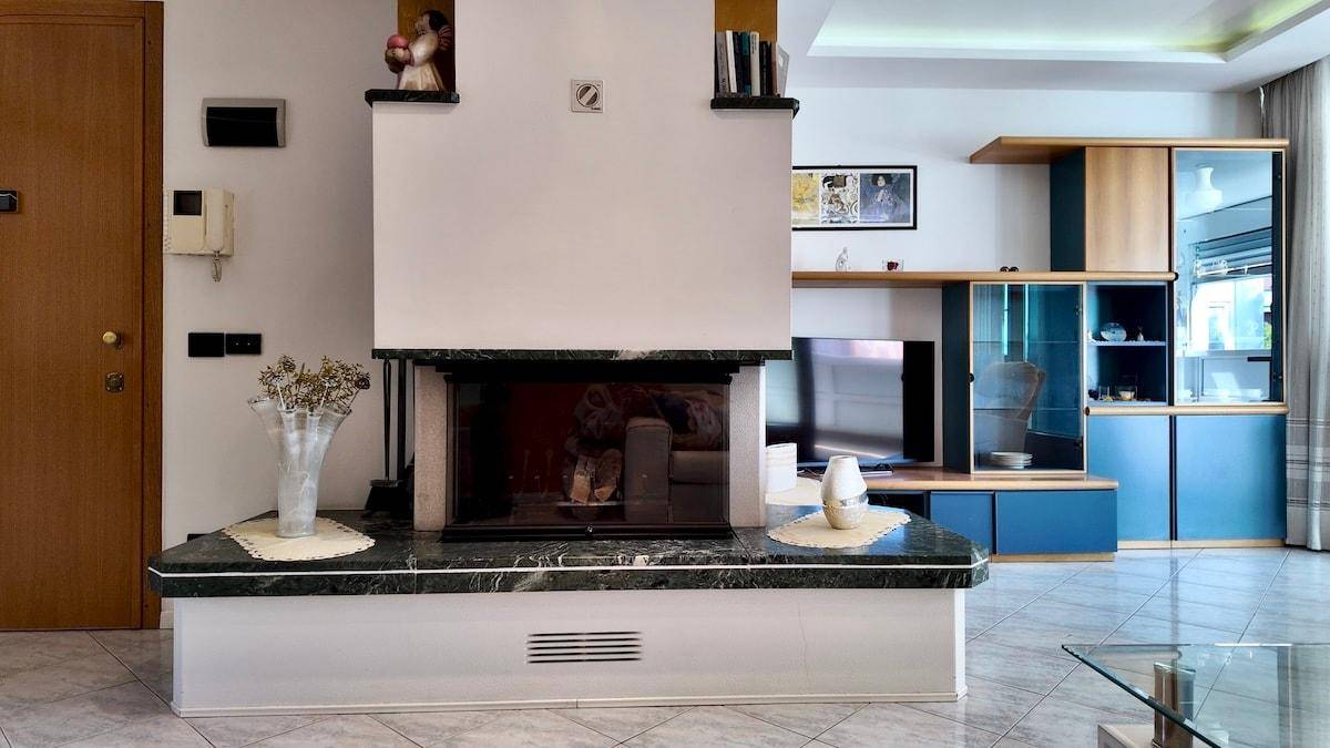 Wohnzimmer mit Kamin, TV-Bereich und blauen Schränken, die Stauraum bieten.