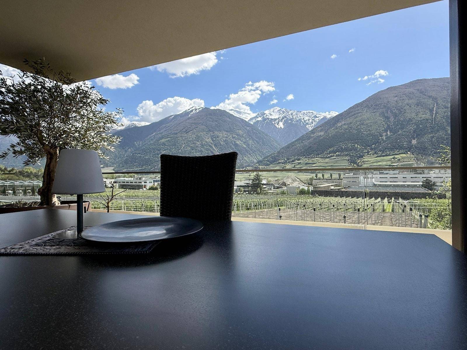 Terrasse mit Esstisch und atemberaubendem Panoramablick auf die umliegende Berg- und Weinlandschaft.