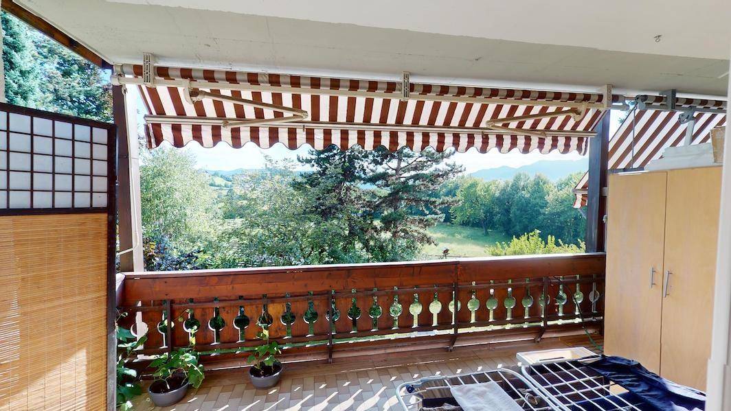 Geräumiger Balkon mit Markise, Holzbalkon und weitem Blick in die Natur.