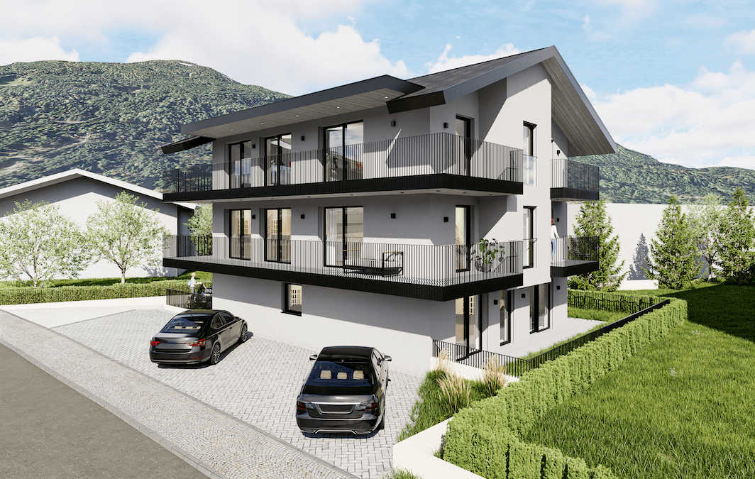 Moderne Wohnanlage mit mehreren Balkonen und Parkplätzen vor einer beeindruckenden Bergkulisse.