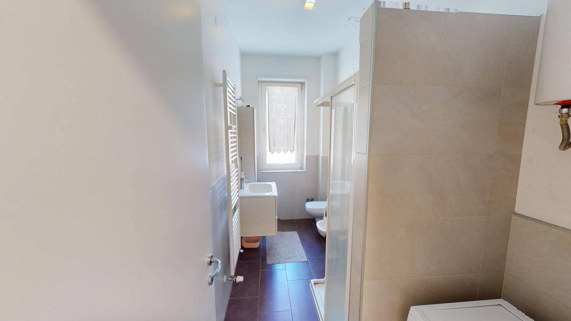 Badezimmer mit Dusche, Waschtisch, Bidet und Fenster für Tageslicht.
