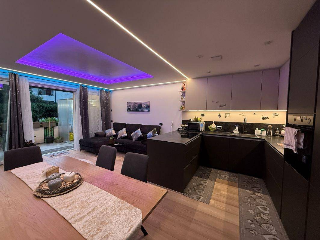 Offene Küche mit Essbereich und Wohnzimmer, beleuchtet durch moderne LED-Streifen.