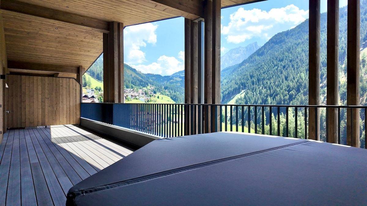 Geräumiger Balkon mit abgedecktem Whirlpool und weitem Blick auf das grüne Tal und die Berge.